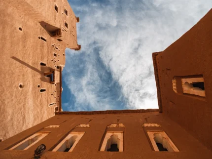 Upward view of Kasbah Taourirt’s adobe towers against a clear blue Moroccan sky